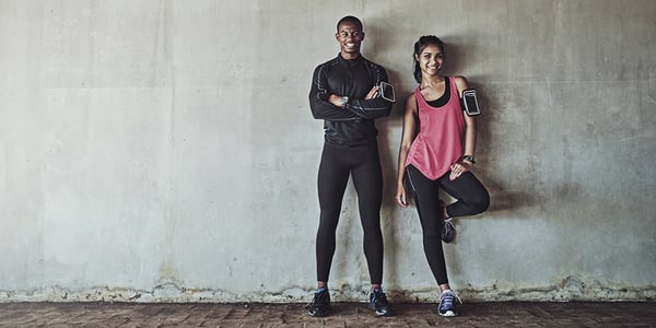 Homme et femme en vêtements de sport appuyés contre un mur