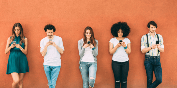 Personnes appuyées contre un mur qui regardent leur téléphone cellulaire