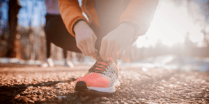 Personne accroupie qui attache ses souliers de course