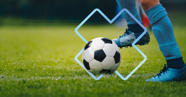 Pied qui frappe un ballon de soccer sur un terrain de gazon